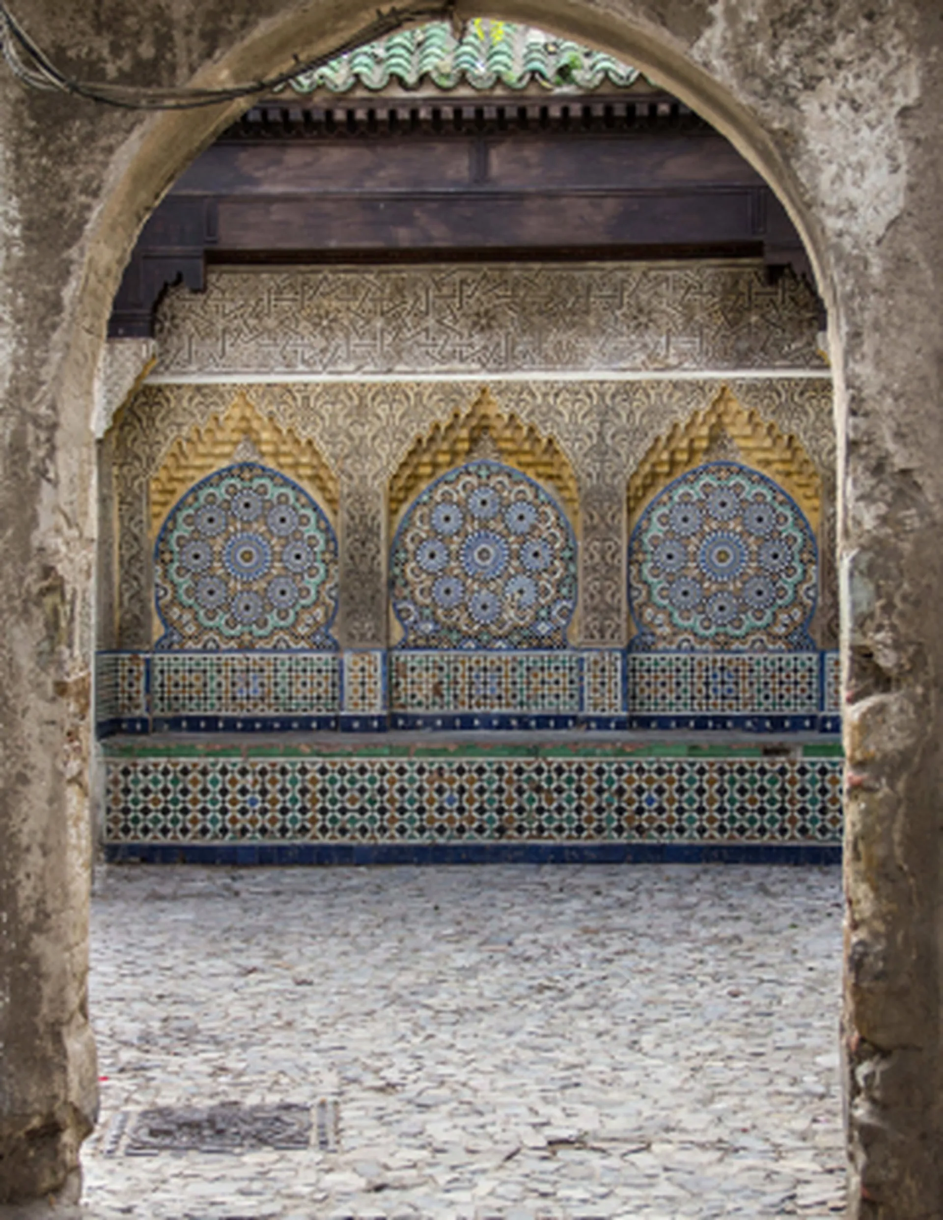 A zellige fountain seen through an arch in the Medina